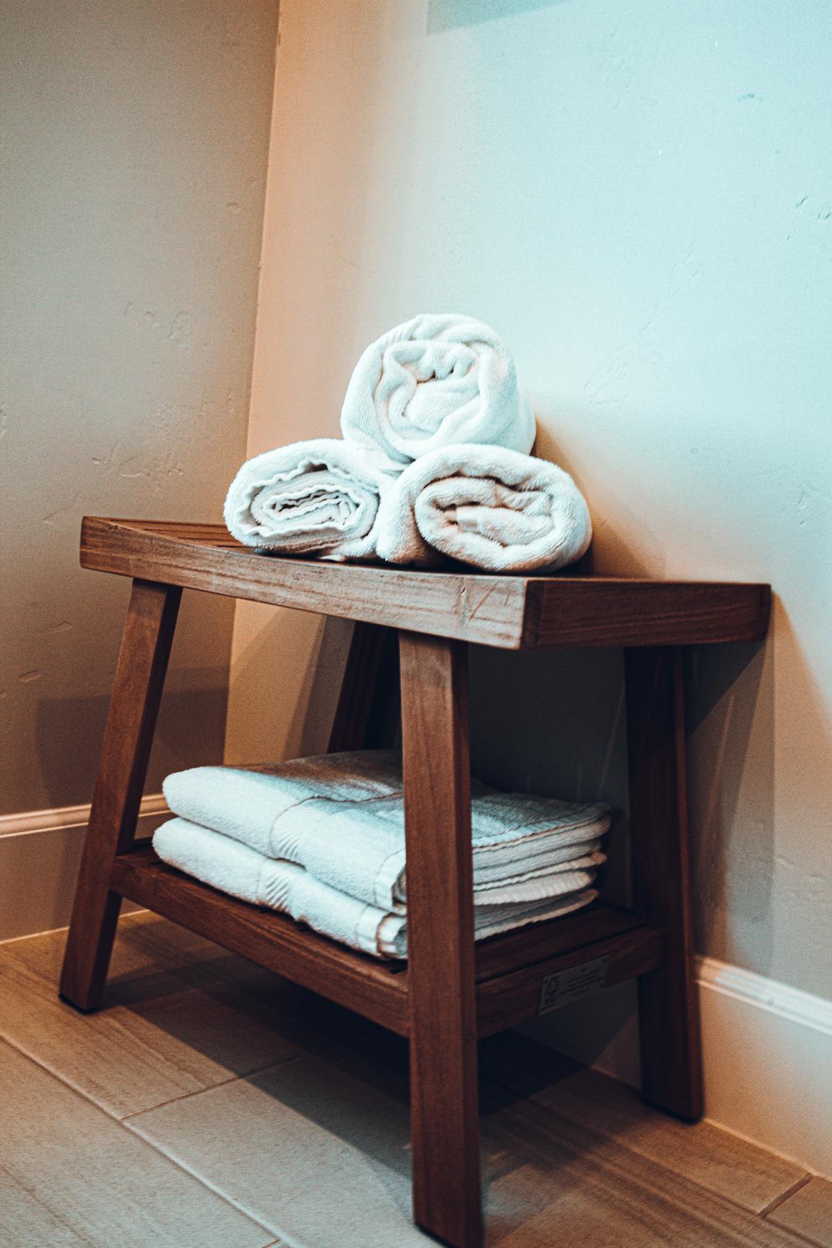 White folded linens on a wooden shelf, warm natural light